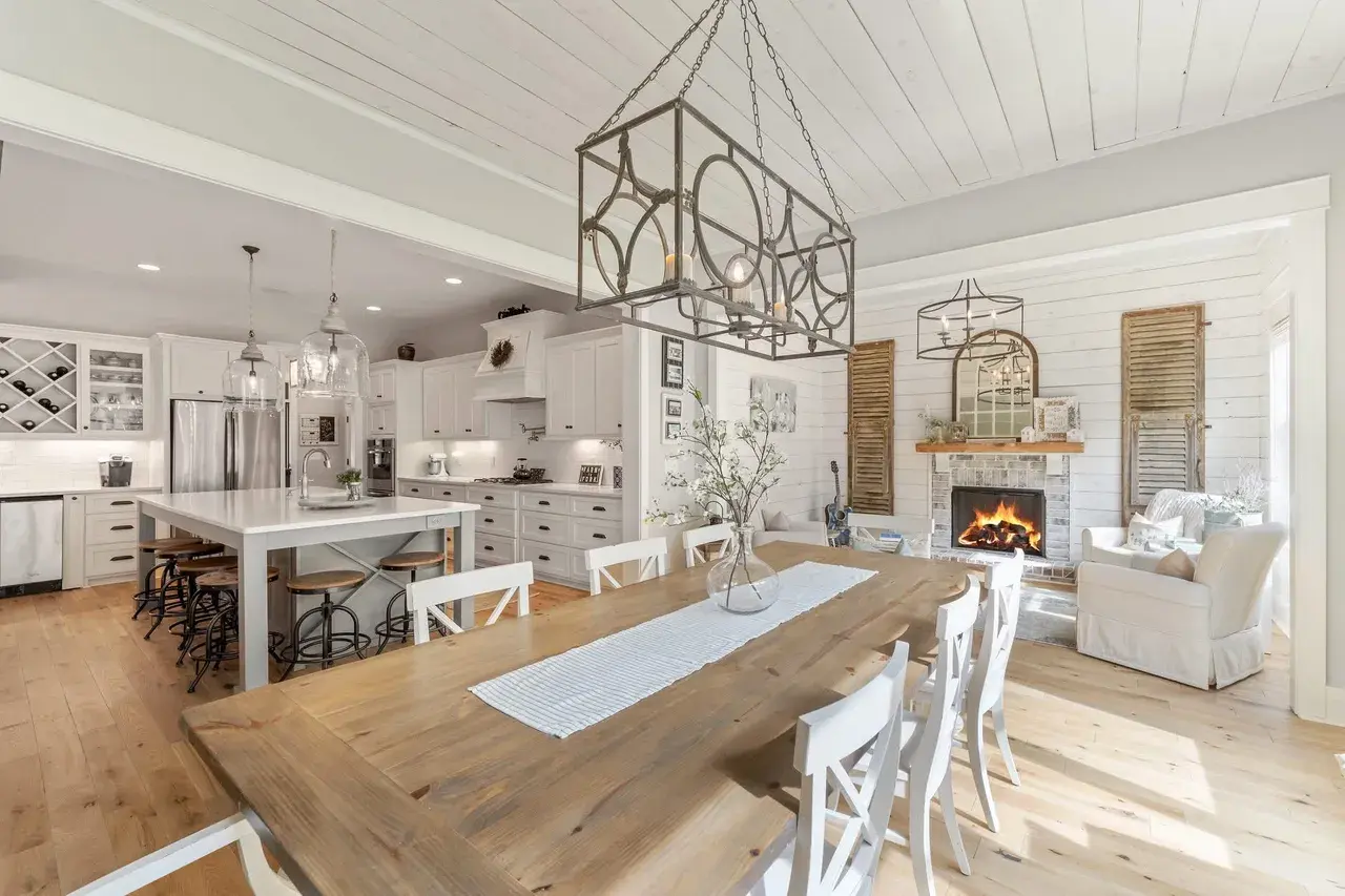 Open kitchen and dining area with a shiplap ceiling, lantern chandeliers and a stone fireplace in a Waxhaw, NC home