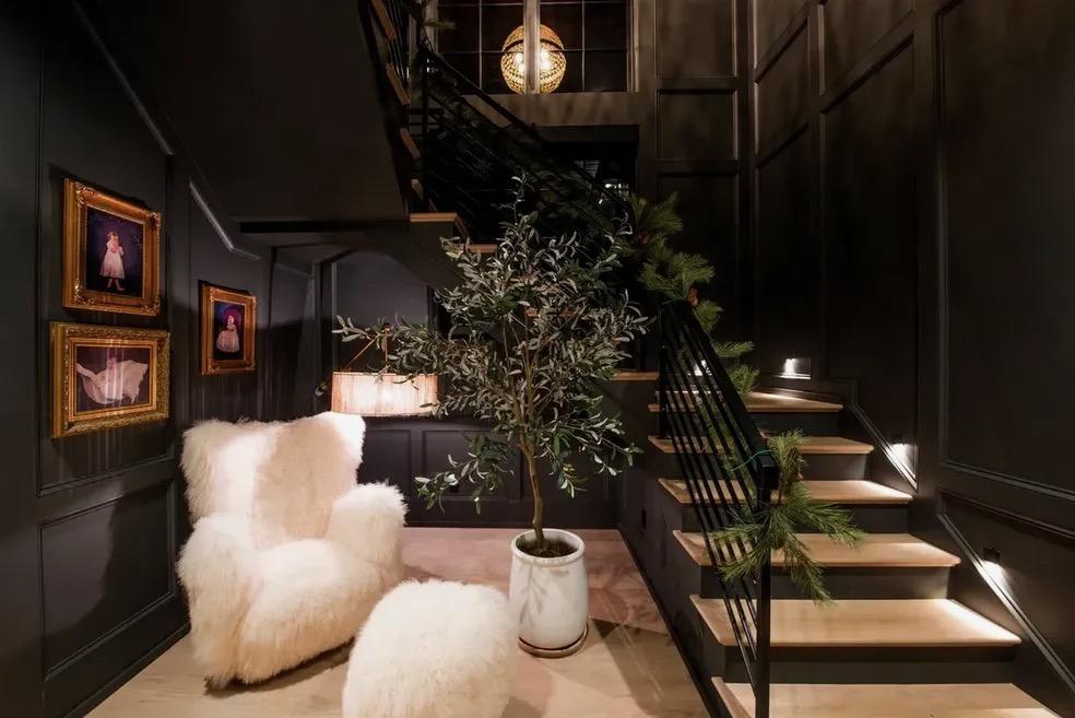 Dark paneled staircase with wood treads, a black metal railing and lit steps in a Waxhaw, NC home