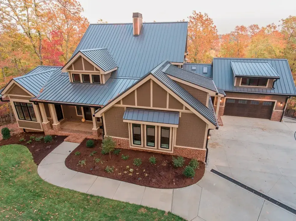 Finished craftsman style home with a standing seam metal roof, brick accents and a three-car garage