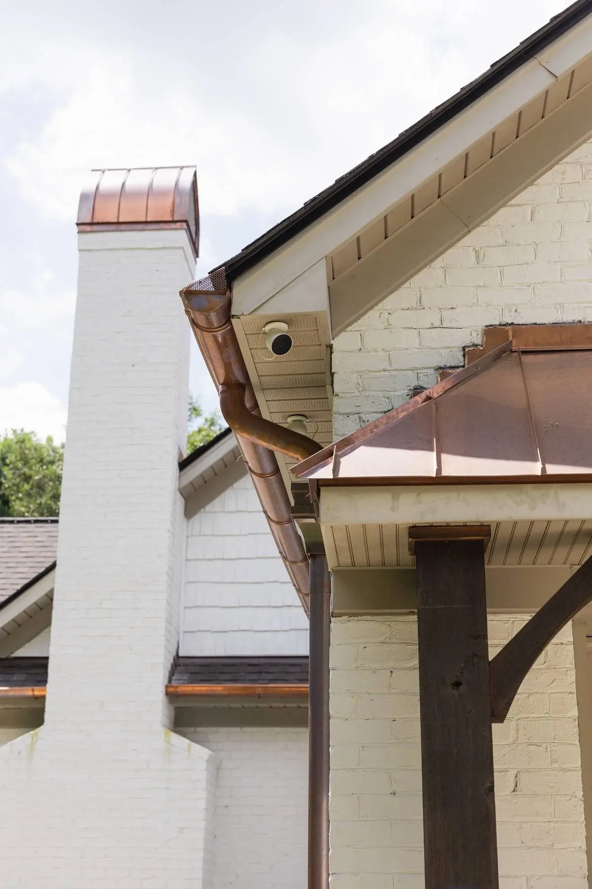 Close view of copper gutters, a downspout and a copper chimney cap on a Weddington, NC home