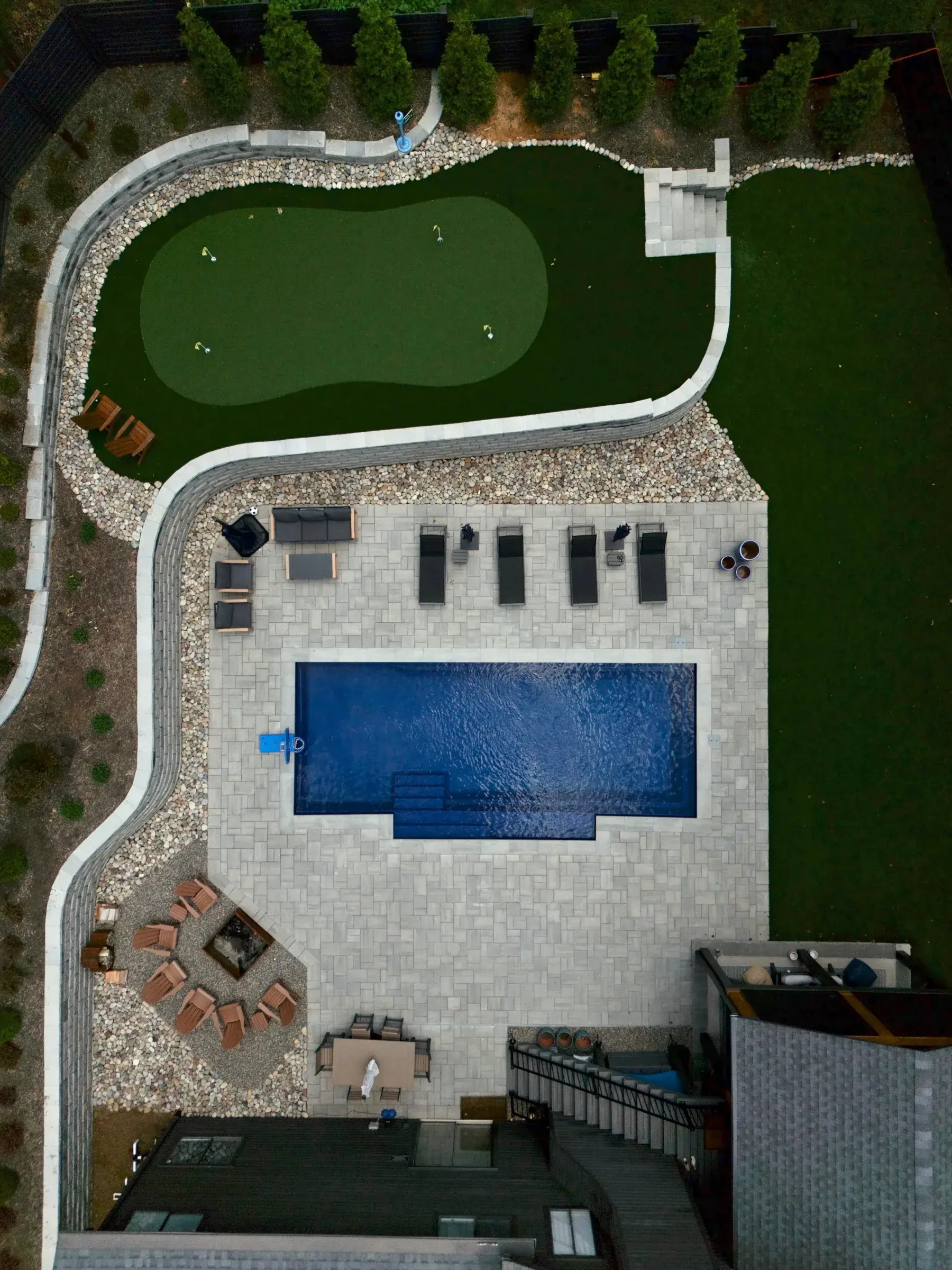 Aerial view of a Charlotte, NC backyard with an inground pool, putting green, paver patio and a fire pit