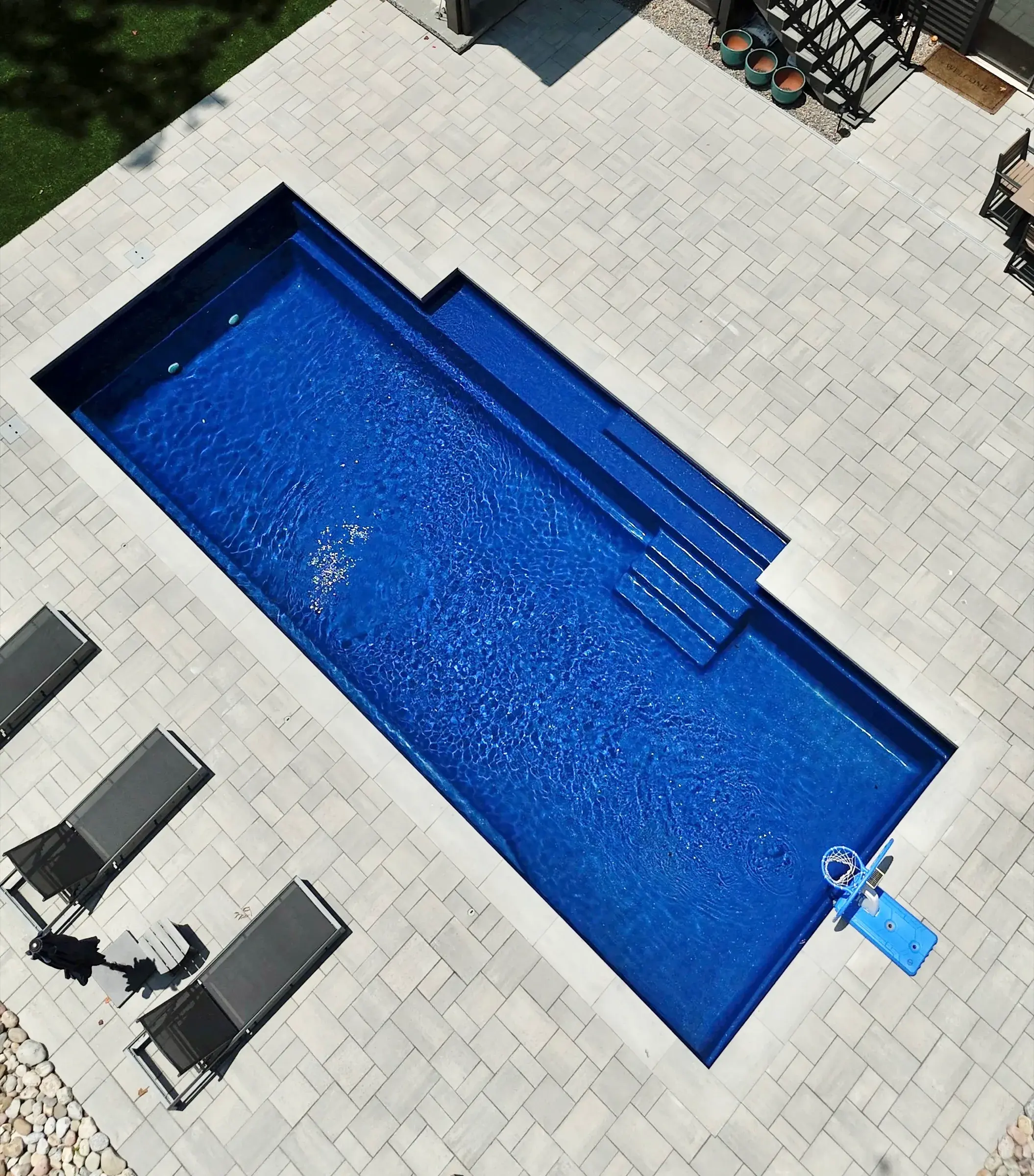 Overhead view of a rectangular inground pool with steps, a tanning ledge and a paver deck in Charlotte, NC