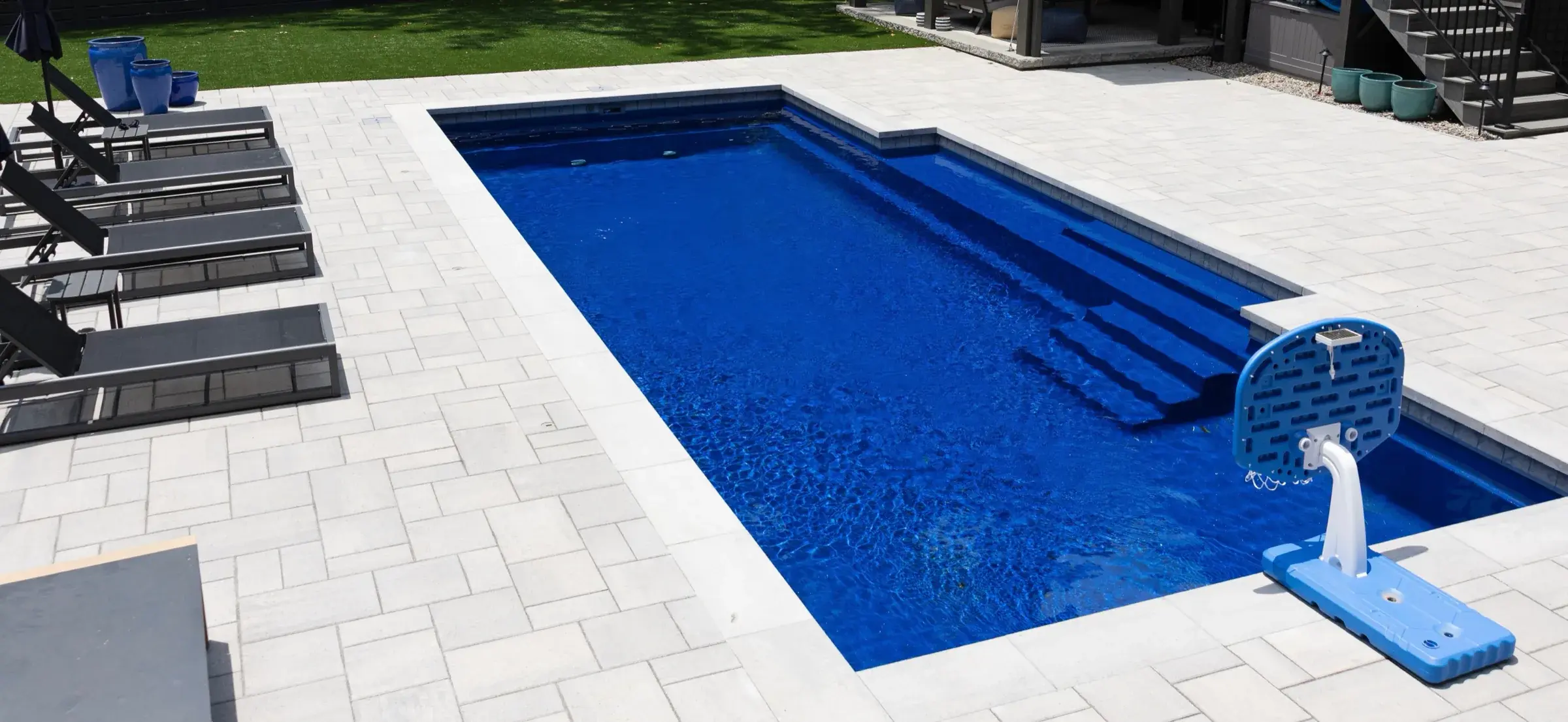 Inground pool with a poolside basketball hoop, lounge chairs and a wide paver deck in Charlotte, NC