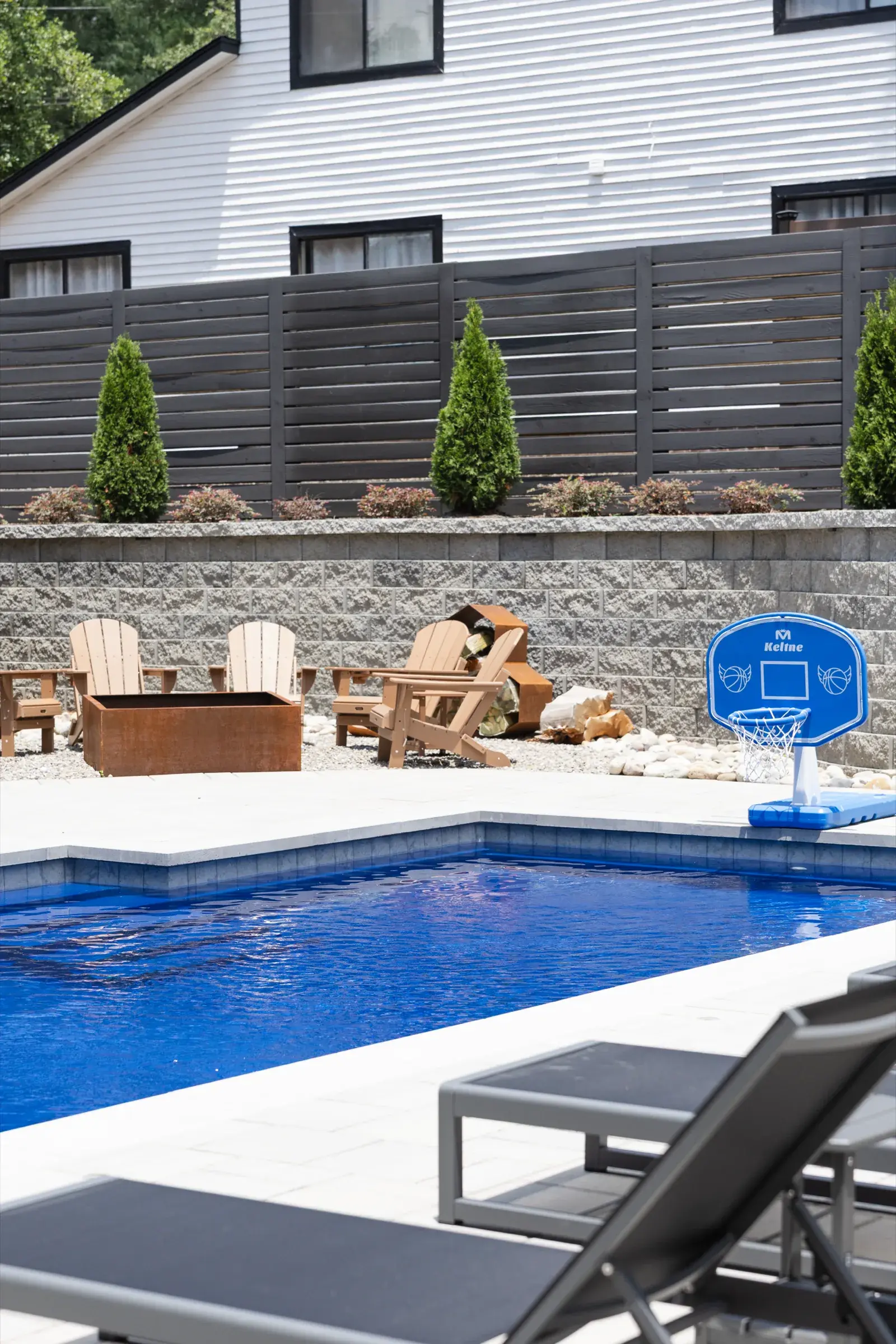 Poolside view of a fire pit, stacked stone retaining wall and horizontal privacy fence in a Charlotte, NC backyard
