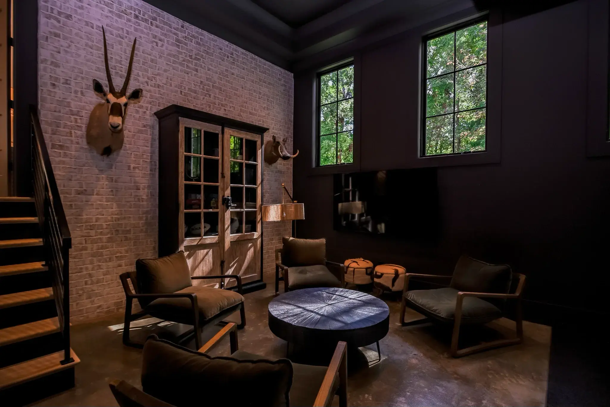 Lounge with a whitewashed brick wall, dark painted ceiling, leather chairs and a round coffee table