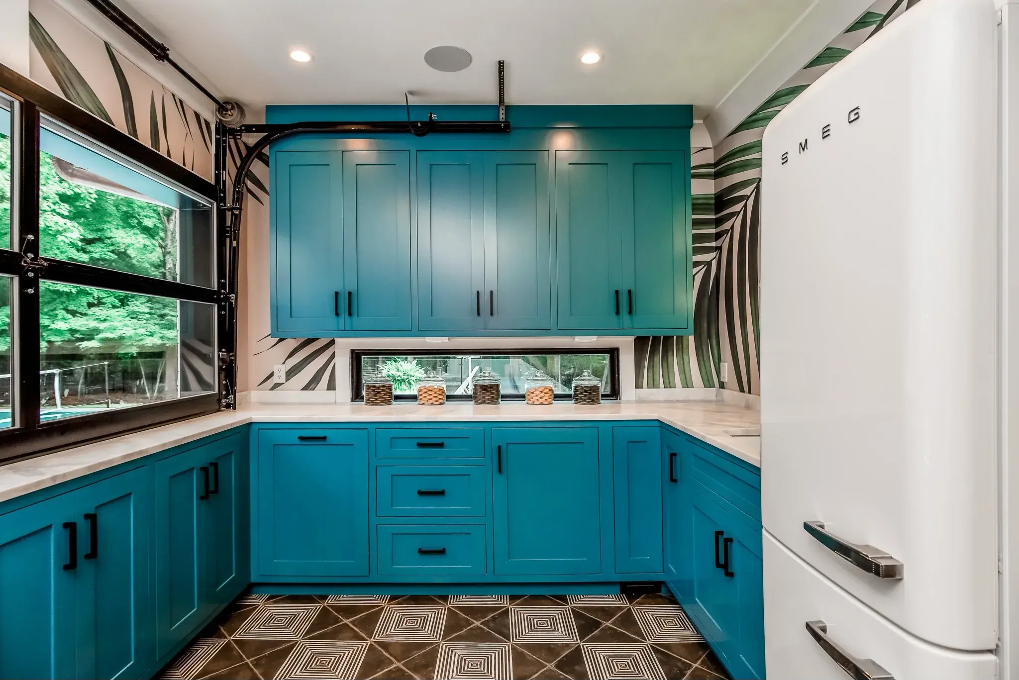 Kitchenette with teal cabinets, palm print wallpaper, a retro white refrigerator and patterned floor tile