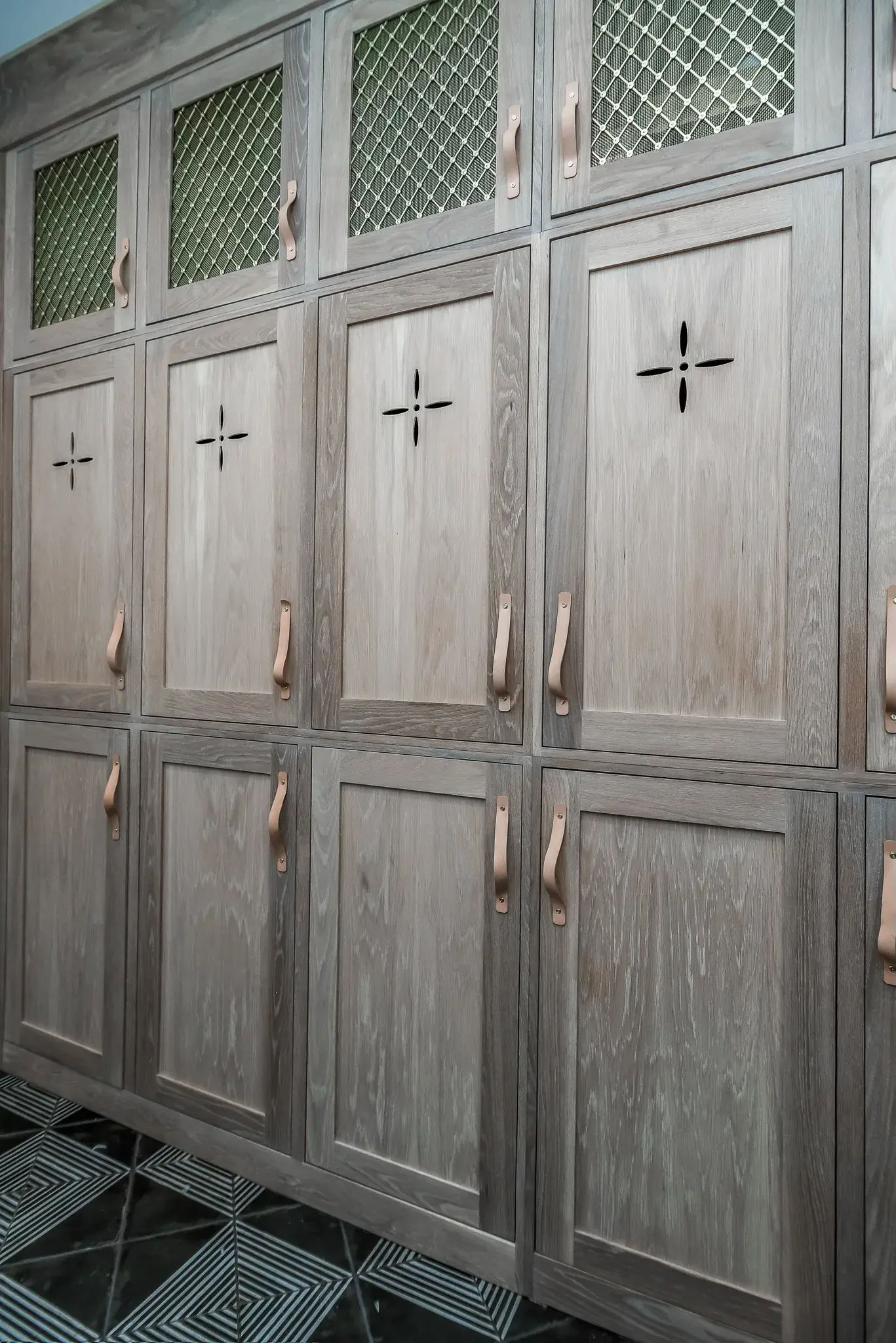 Close view of white oak cabinet doors with brass mesh inserts, leather pulls and cutout detailing